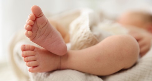Photo of Cute newborn child lying in baby nest indoors, closeup