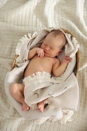 Photo of Cute newborn child sleeping in baby nest on bed, top view