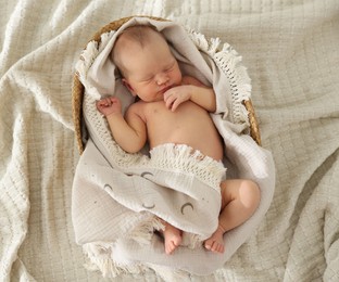 Photo of Cute newborn child sleeping in baby nest on bed, top view