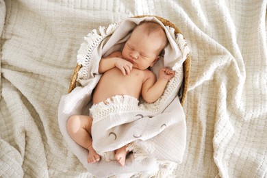 Photo of Cute newborn child sleeping in baby nest on bed, top view