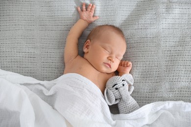 Photo of Cute newborn baby with toy on bed, top view