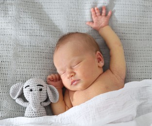 Photo of Cute newborn baby with toy on bed, top view