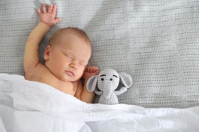 Photo of Cute newborn baby with toy on bed, top view. Space for text
