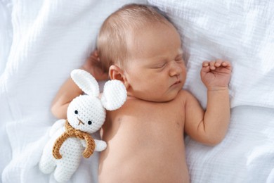 Photo of Cute newborn baby with toy on bed, top view