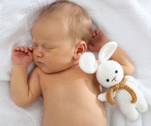 Photo of Cute newborn baby with toy on bed, top view