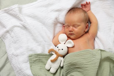 Photo of Cute newborn baby with toy bunny on bed, top view. Space for text