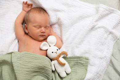 Photo of Cute newborn baby with toy bunny on bed, top view. Space for text