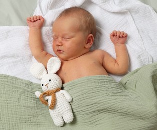 Photo of Cute newborn baby with toy bunny on bed, top view
