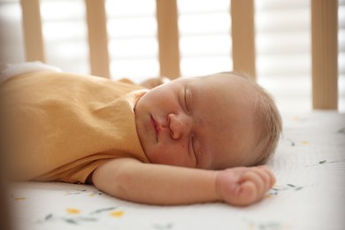 Photo of Cute newborn baby lying in crib indoors