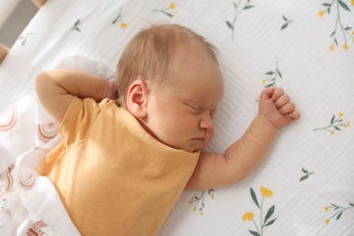 Photo of Cute newborn baby lying in crib, above view