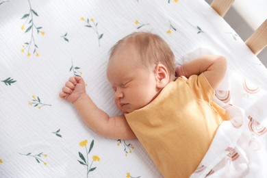 Photo of Cute newborn baby lying in crib, above view
