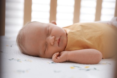 Photo of Cute newborn baby lying in crib indoors