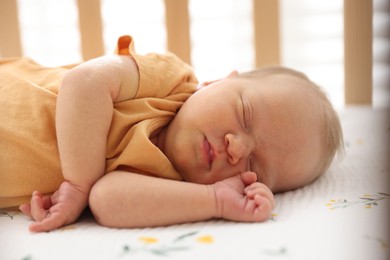 Photo of Cute newborn baby lying in crib indoors
