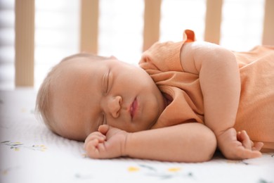 Photo of Cute newborn baby lying in crib indoors