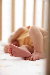 Photo of Cute newborn baby lying in crib, closeup