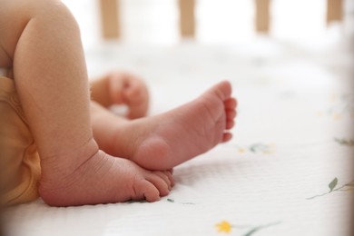 Photo of Cute newborn baby lying in crib, closeup. Space for text