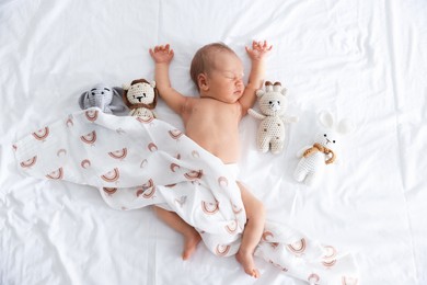 Photo of Cute newborn baby and different toys on bed, top view