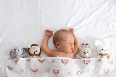 Photo of Cute newborn baby and different toys on bed, top view