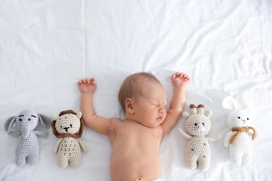 Photo of Cute newborn baby and different toys on bed, top view