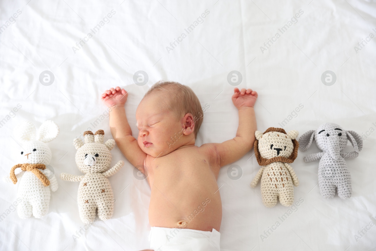 Cute newborn baby and different toys on bed, top view Photo of Cute newborn baby and different toys on bed, top view