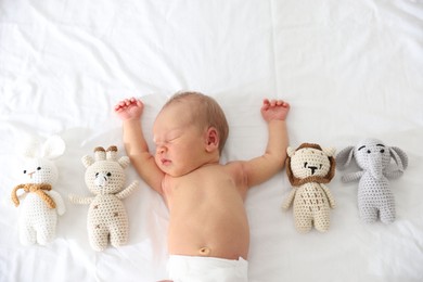 Photo of Cute newborn baby and different toys on bed, top view