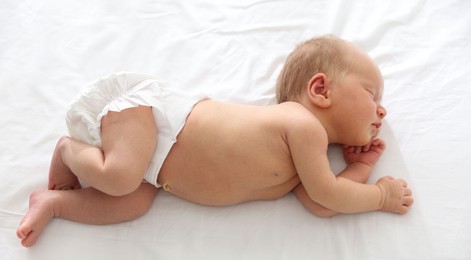 Photo of Cute newborn baby sleeping on bed, above view