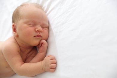 Photo of Cute newborn baby sleeping on bed, space for text