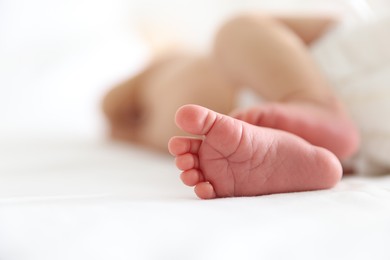 Photo of Cute newborn baby lying on bed indoors, closeup. Space for text