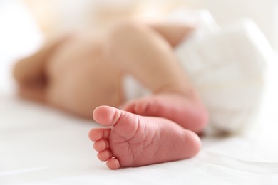 Photo of Cute newborn baby lying on bed indoors, closeup