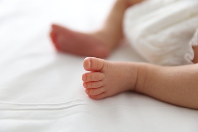 Photo of Cute newborn baby lying on bed indoors, closeup. Space for text