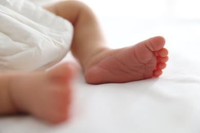 Photo of Cute newborn baby lying on bed indoors, closeup