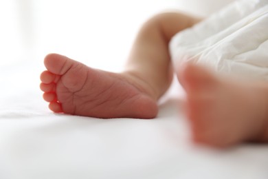 Photo of Cute newborn baby lying on bed indoors, closeup
