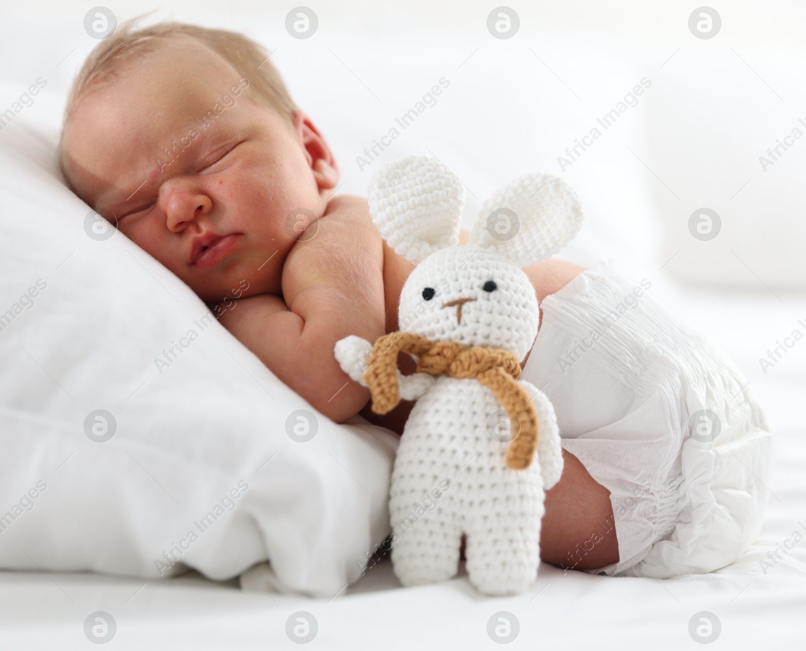 Cute newborn baby sleeping on pillow and toy bunny indoors Photo of Cute newborn baby sleeping on pillow and toy bunny indoors
