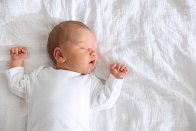 Photo of Cute newborn baby sleeping on bed, top view. Space for text