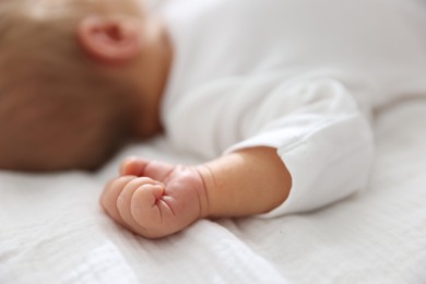 Photo of Cute newborn baby lying on bed indoors, closeup