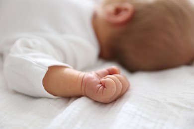 Photo of Cute newborn baby lying on bed indoors, closeup