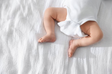 Photo of Cute newborn baby lying on bed indoors, top view. Space for text
