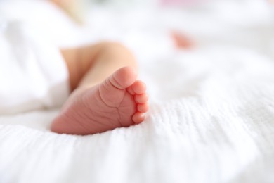 Photo of Cute newborn baby lying on bed indoors, closeup. Space for text
