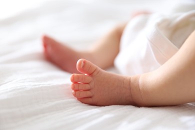 Photo of Cute newborn baby lying on bed indoors, closeup. Space for text