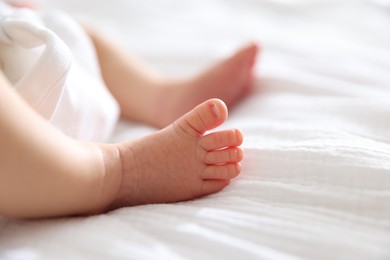 Photo of Cute newborn baby lying on bed indoors, closeup. Space for text