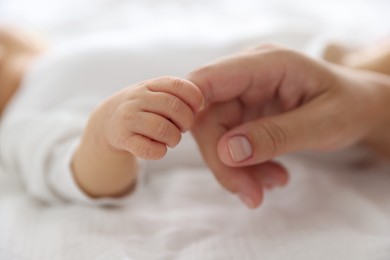 Photo of Mother with her cute newborn baby on bed indoors, closeup