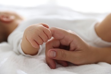 Photo of Mother with her cute newborn baby on bed indoors, closeup