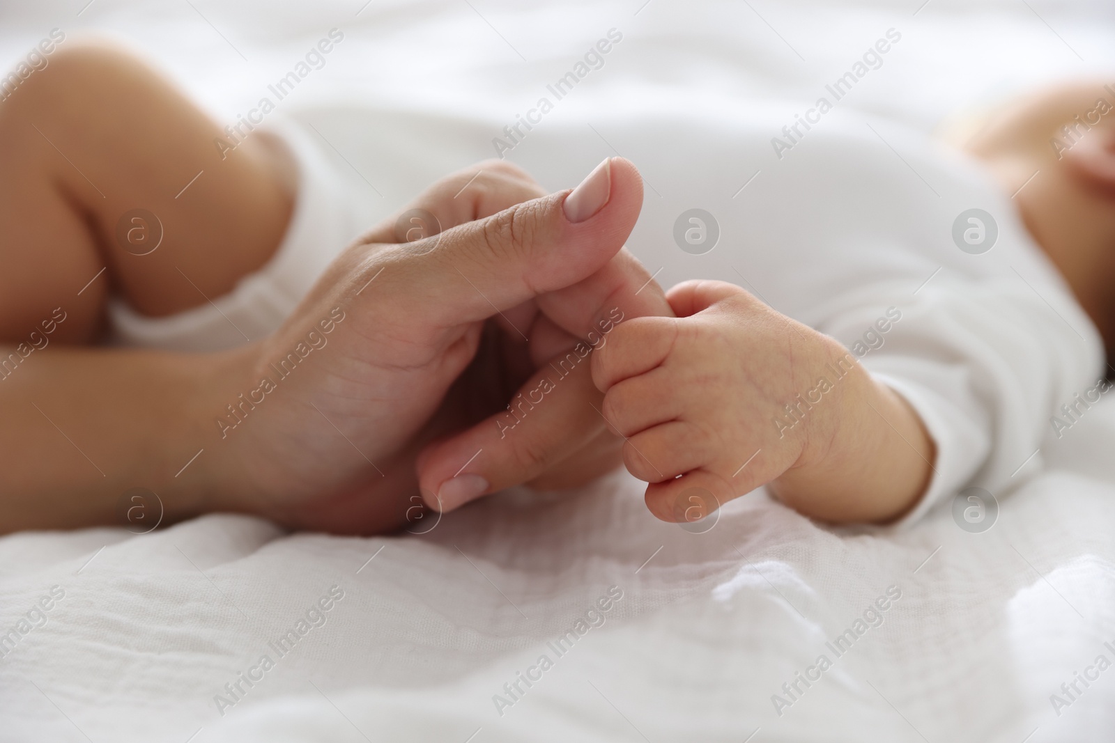 Mother with her cute newborn baby on bed indoors, closeup Photo of Mother with her cute newborn baby on bed indoors, closeup