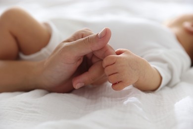 Photo of Mother with her cute newborn baby on bed indoors, closeup