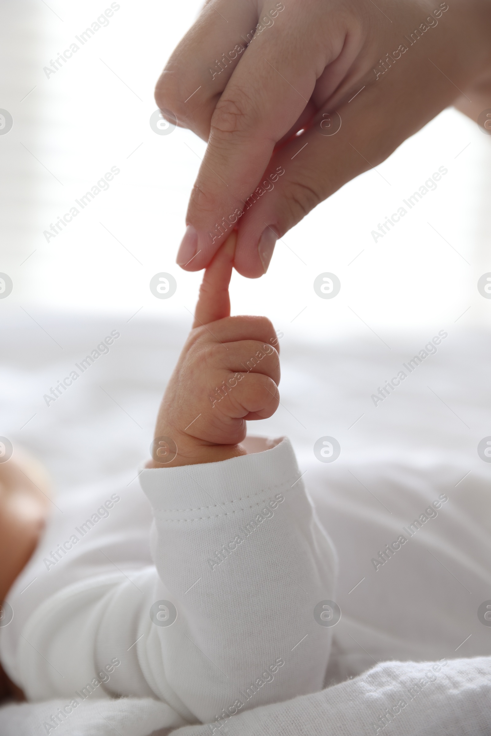 Mother with her cute newborn baby on bed indoors, closeup Photo of Mother with her cute newborn baby on bed indoors, closeup