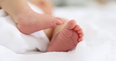 Photo of Cute newborn baby lying on bed, closeup