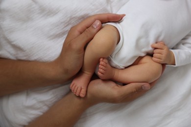 Photo of Father with his cute newborn baby on bed, top view