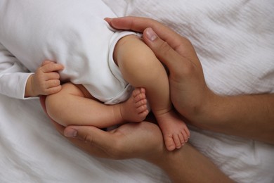 Photo of Father with his cute newborn baby on bed, top view