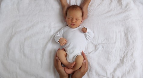 Photo of Parents with their cute newborn baby on bed, top view