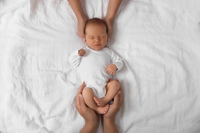 Photo of Parents with their cute newborn baby on bed, top view
